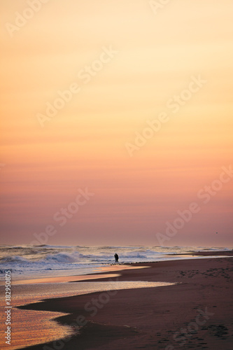 Couple holding each other close on the beach as waves break during sunset