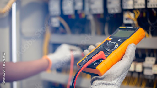 Electrician engineer uses a multimeter to test the electrical installation and power line current in an electrical system control cabinet. photo