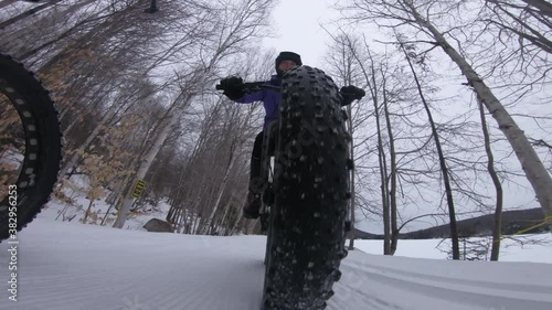 Biking in winter on fat bike. Fat biker riding bicycle in the snow in winter. Close up action shot of fat tire bike wheels in the snow. Woman living healthy winter sports lifestyle. photo