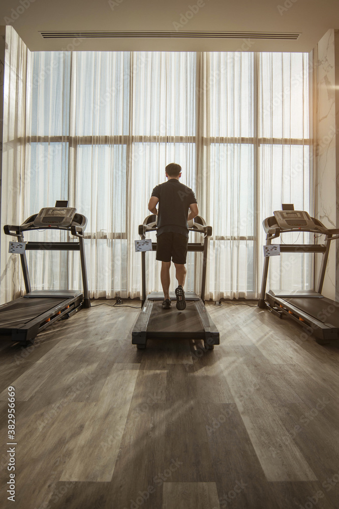 Fototapeta premium Man running on a treadmill. running on treadmill with sunlight.