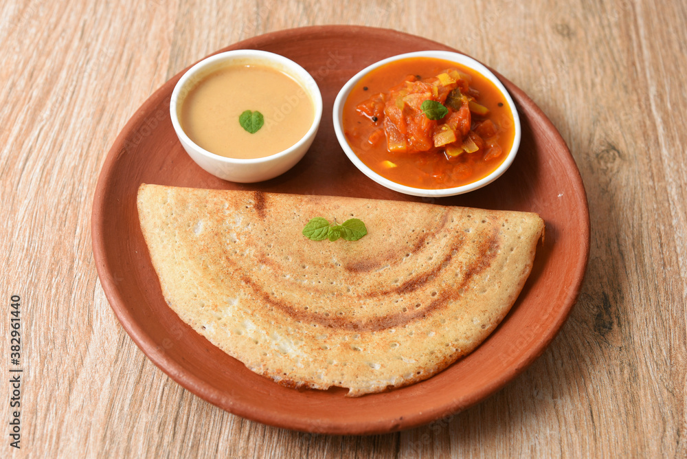 Dosa, ghee roast, coconut chutney and sambar popular South Indian Breakfast, Kerala, Tamil Nadu India. Top view of Masala dosa, pancake stuffed with potato, tomato curry side dish. Vegetarian food. Dosa, ghee roast, coconut chutney and sambar popular South Indian Breakfast, Kerala, Tamil Nadu India. Top view of Masala dosa, pancake stuffed with potato, tomato curry side dish. Vegetarian food.