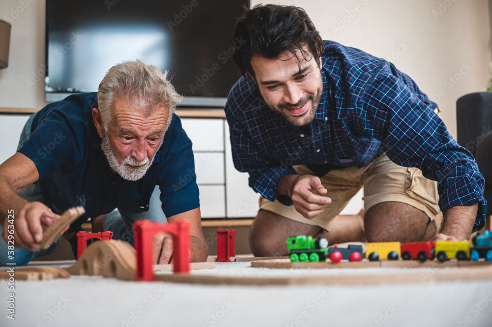 Old times remember. Positive delighted good looking father and son sitting together and playing the children toy. Old times remember. Positive delighted good looking father and son sitting together and playing the children toy.