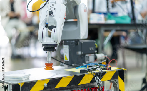Man is holding a teach pendant to control a robot arm that is integrated into a smart factory production line. automation line which is equipped with sensors and robot arm. Selective Focus. 