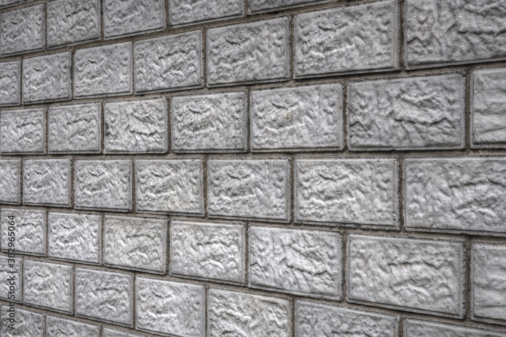 Fototapeta premium Aged background or wallpaper on a construction theme. The wall of the building is made of gray concrete blocks. The masonry seams form a perspective. Dark backdrop on the subject of housing repairs
