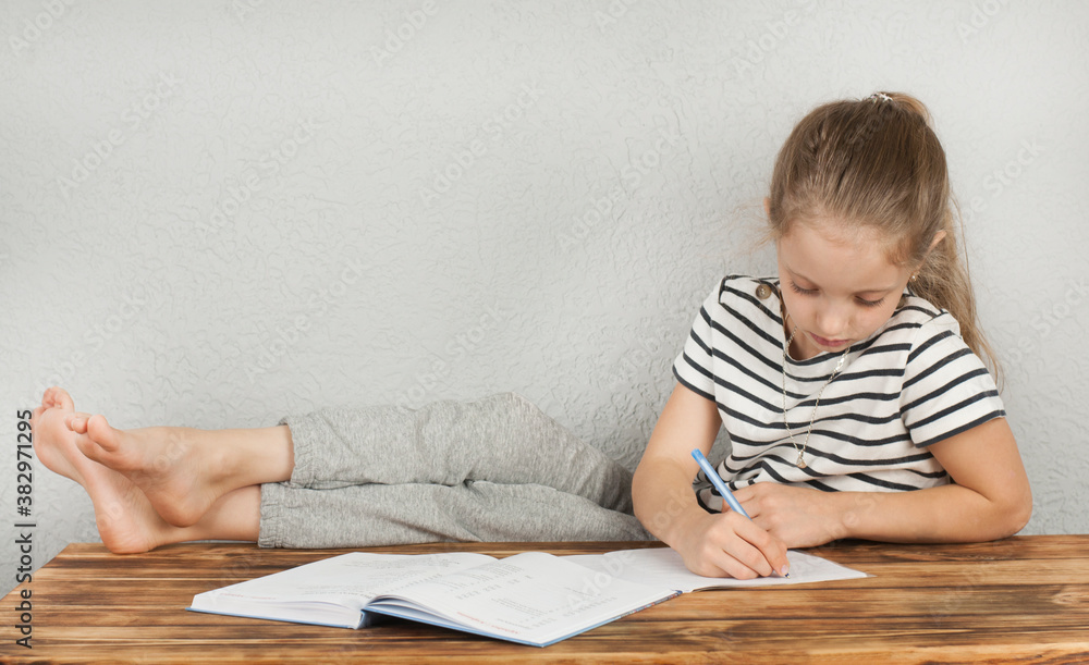 Girl 8 - 10 years old doing homework sitting at a wooden table. Homeschooling Girl 8 - 10 years old doing homework sitting at a wooden table. Homeschooling
