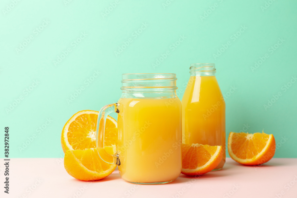 Glass jars with orange juice against mint background Glass jars with orange juice against mint background