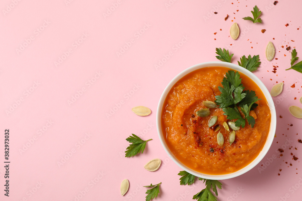 Composition with bowl of pumpkin soup on pink background, top view Composition with bowl of pumpkin soup on pink background, top view