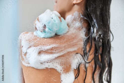 Obraz na plátne Brunette young woman washing body with exfoliating bath sponge