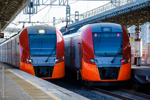 Two modern, eco-friendly red trains of the Moscow Central Circle metro station at the station during the day. High-speed, comfortable and Begorodsky public transport.