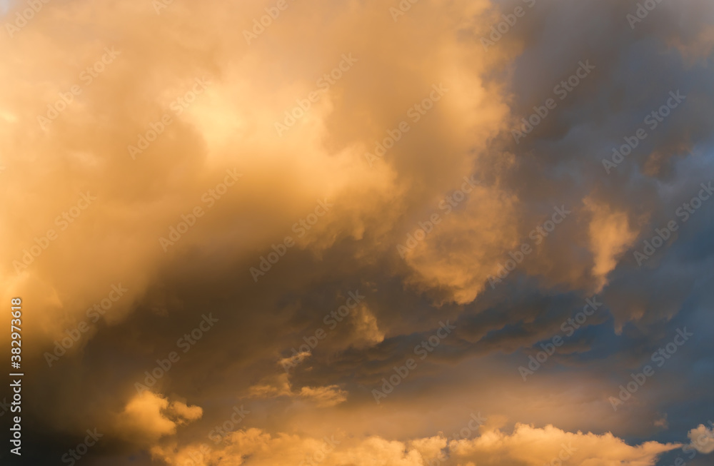 Section of sky with cumulus and rain clouds at sunset
