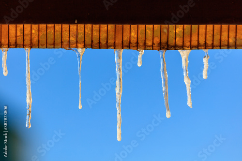 Icicles in winter against a blue sky.