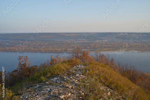 Autumn view from the mountain to the big river, in the forest with Golden leaves and green fir trees. Autumn time in the forest. © nikolay_alekhin