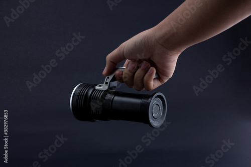 Fotografia hand holding a flashlight on dark background.