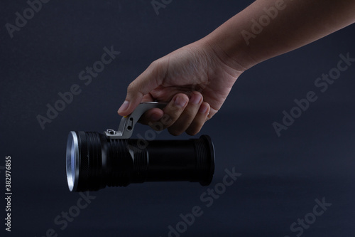 hand holding a flashlight on dark background.