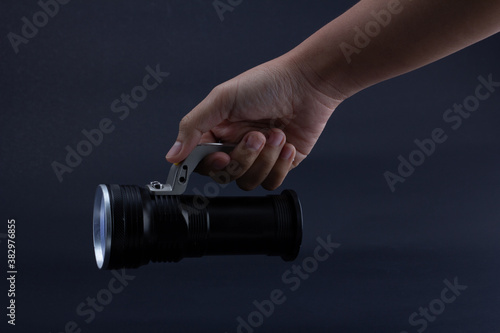 фотографія hand holding a flashlight on dark background.