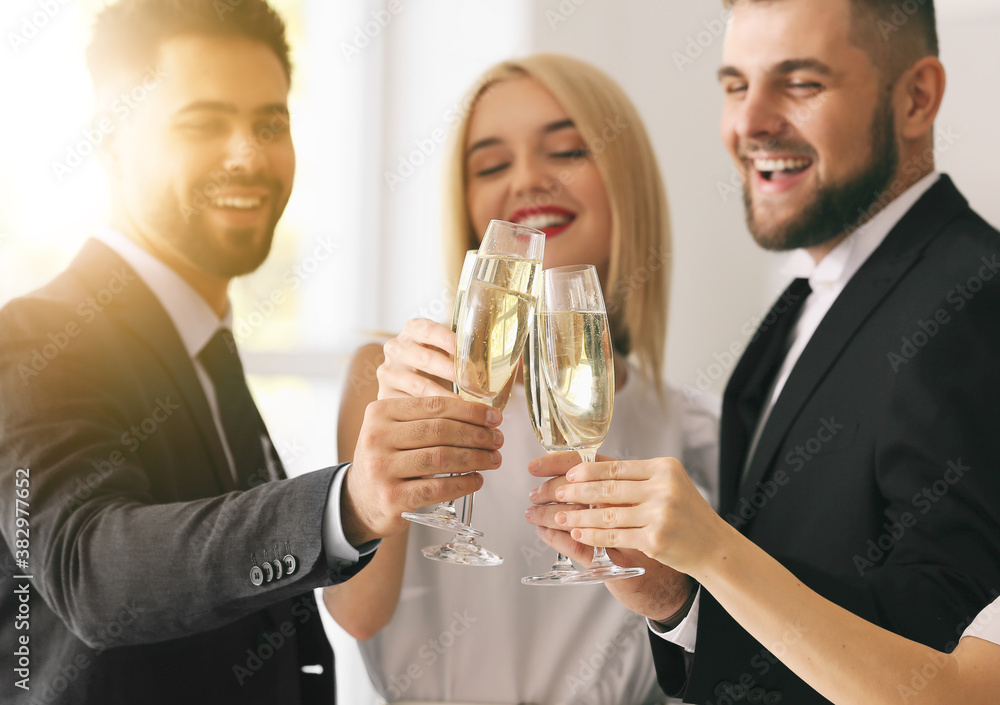 Young people clinking glasses of tasty champagne at party in office Young people clinking glasses of tasty champagne at party in office