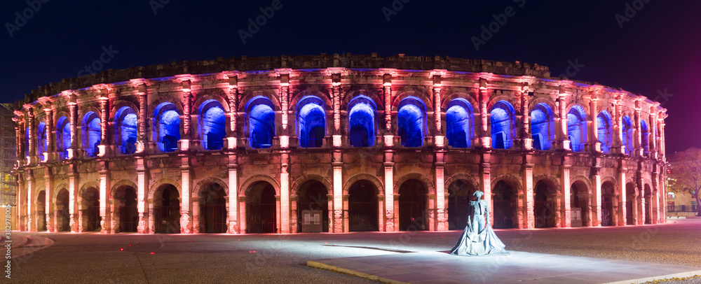 Panorama of illuminated Roman amphitheater in French city of Nimes at night