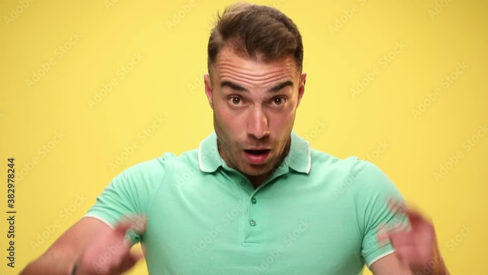 casual handsome man is surprised because of the news he gets, pointing at his head and gesturing a crazy sign on yellow background casual handsome man is surprised because of the news he gets, pointing at his head and gesturing a crazy sign on yellow background