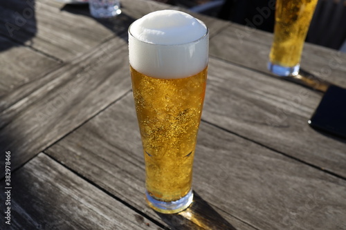 Ein kristallklares Bier mit schönem Bierschaum sonnt sich auf einem Holztisch.