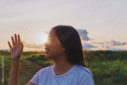 Asian woman standing at grass field with mountain and sunset sky scenic landscape background with copy space.