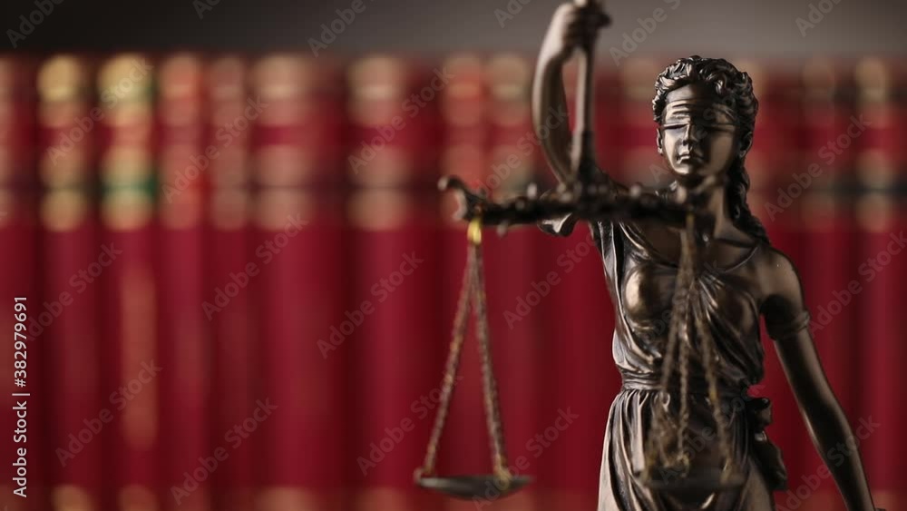 bronze blindfolded goddess representing law statue spinning, holding a scale symbolizing impartiality and two broad sources of law in a university room with a background made of books bronze blindfolded goddess representing law statue spinning, holding a scale symbolizing impartiality and two broad sources of law in a university room with a background made of books