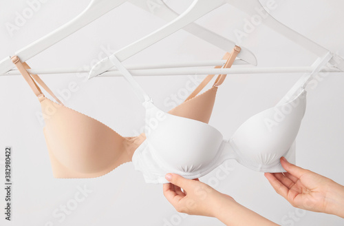 Woman choosing stylish lingerie on light background