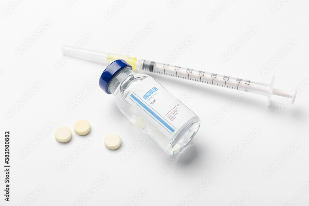 Bottle of insulin with syringe and pills on white background. Diabetes concept Bottle of insulin with syringe and pills on white background. Diabetes concept