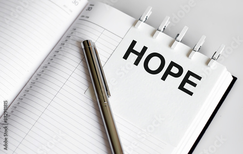 text HOPE on the short note texture background with pen
