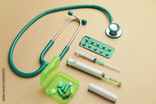 Stethoscope with pills and syringes on color background. Diabetes concept