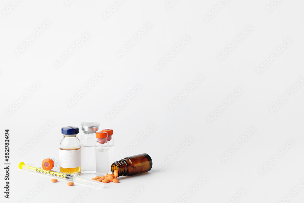 Bottles of insulin with pills and syringe on white background. Diabetes concept Bottles of insulin with pills and syringe on white background. Diabetes concept