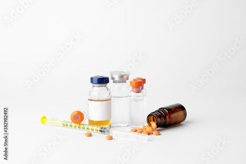 Bottles of insulin with pills and syringe on white background. Diabetes concept