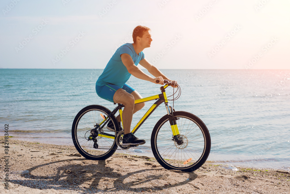 Young man bicycling along a beach