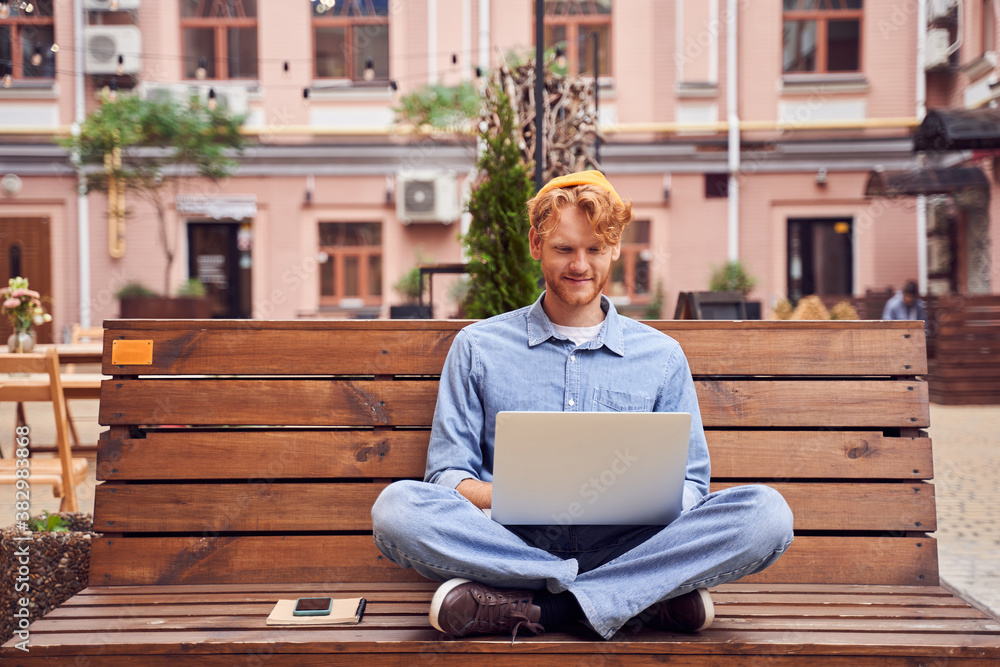 Handsome man working on laptop on the bench Handsome man working on laptop on the bench