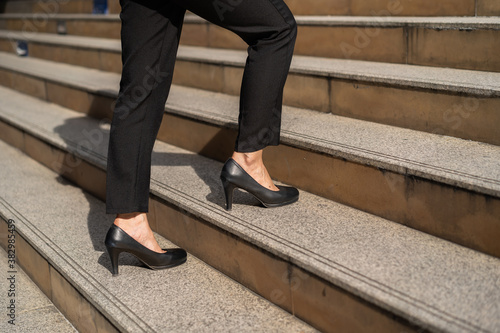 business woman with high heel shoes walking up on the stairs in city