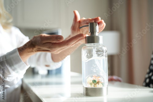 Female hands using wash hand sanitizer gel pump dispenser