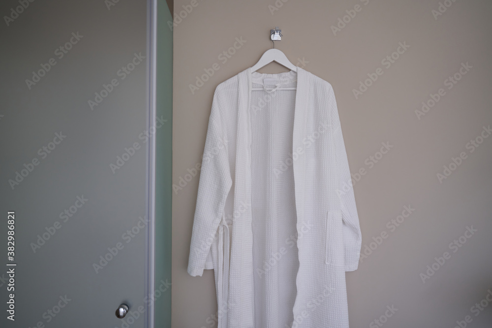 White fresh bathrobe on the brown wall in bathroom White fresh bathrobe on the brown wall in bathroom