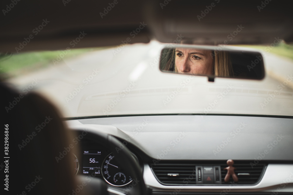 Fototapeta premium Pretty midle aged woman at the steering wheel of her car commuting to work