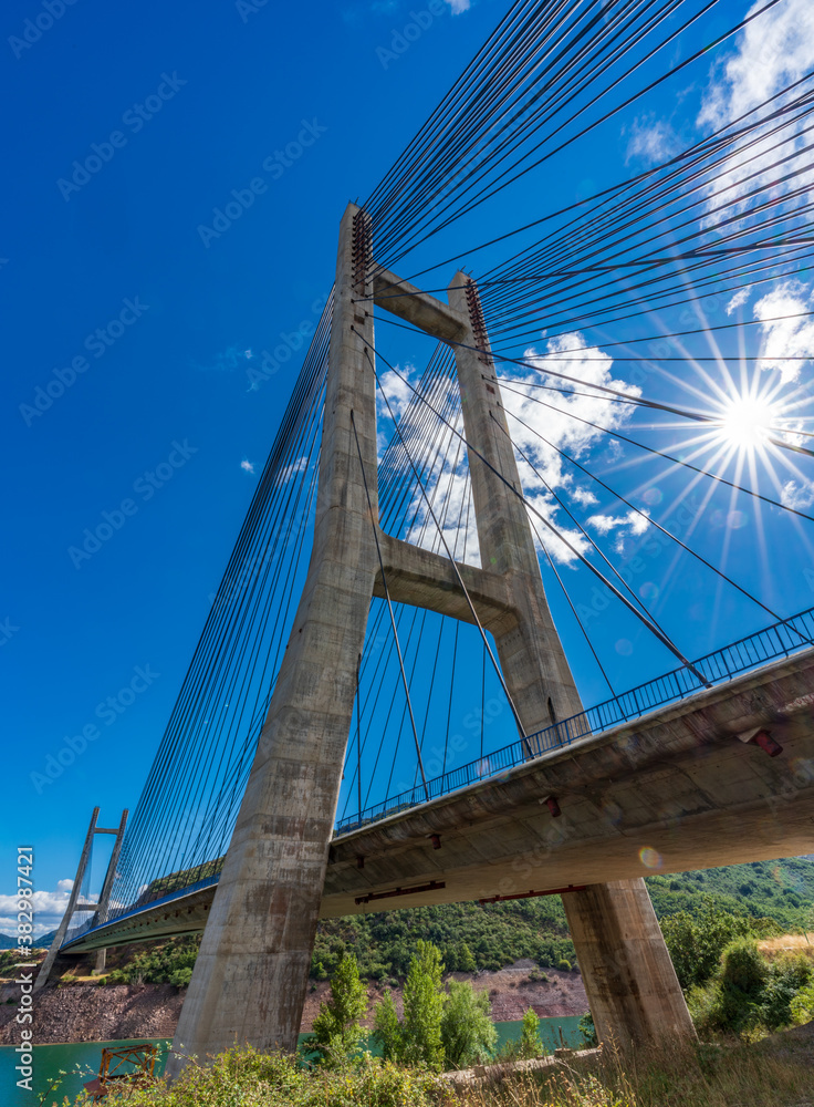 Fototapeta premium Cable suspension bridge over reservoir with starry sun