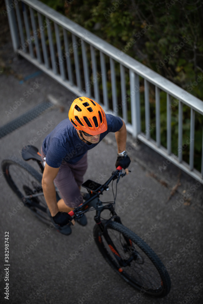 Naklejka premium Cross country mtb biker going for his favorite hills beyond the city limits (top view; shallow DOF)