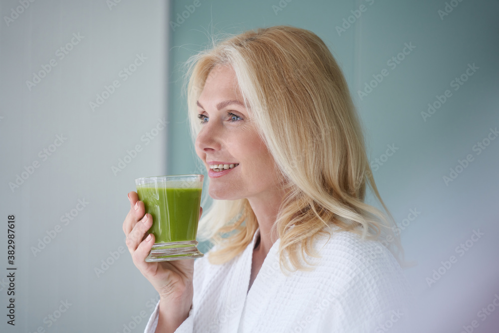 Happy blonde woman standing with healthy drink Happy blonde woman standing with healthy drink
