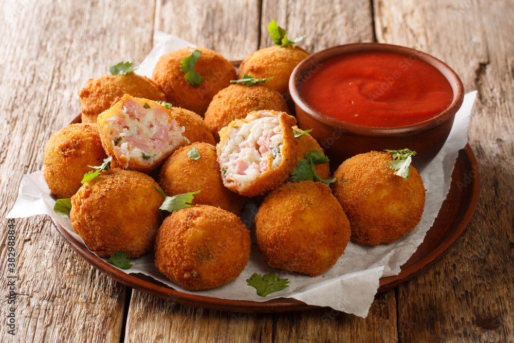 Popular fried hot appetizer sauerkraut balls stuffed with ham served with ketchup close-up in a plate on the table. horizontal