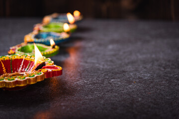 Close up of clay lit light a fire already on Diya or oil lamp, studio shot on concrete background, Decoration of Hinduism rangoli, Happy celebration Deepavali or Diwali festival concept