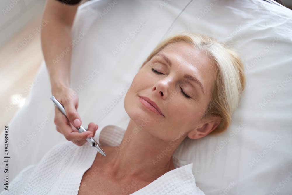 Adult lady in white bathrobe relaxing in beauty clinic