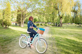 Attractive black young girl with a bicycle on a walk in the park in a crowded place. Woman posing at camera while sitting on a bicycle