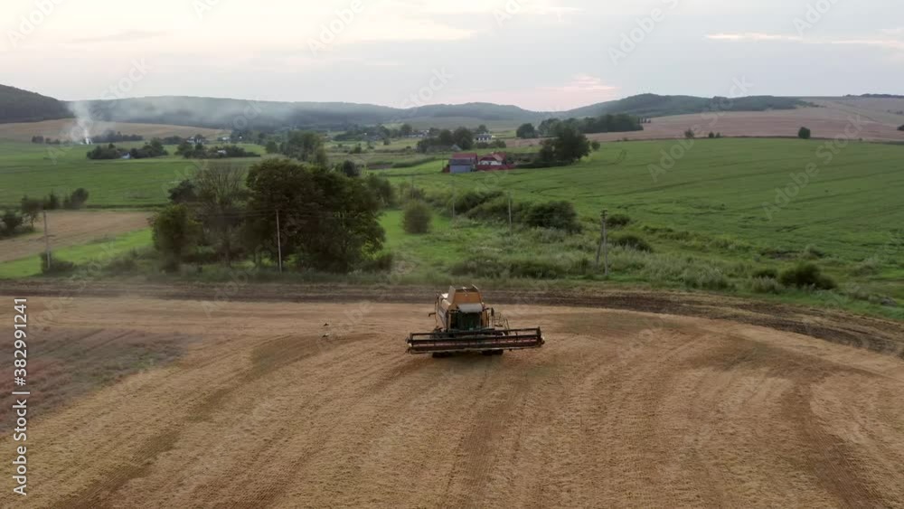 Combine harvester and tractor at harvest at sunset Combine harvester and tractor at harvest at sunset