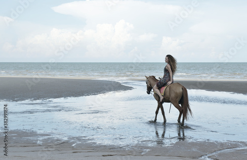 Woman riding horse on the beach over sea and sky, soft tone, Summer holiday and travel concept