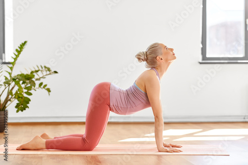 fitness, people and healthy lifestyle concept - young woman doing cow pose at yoga studio