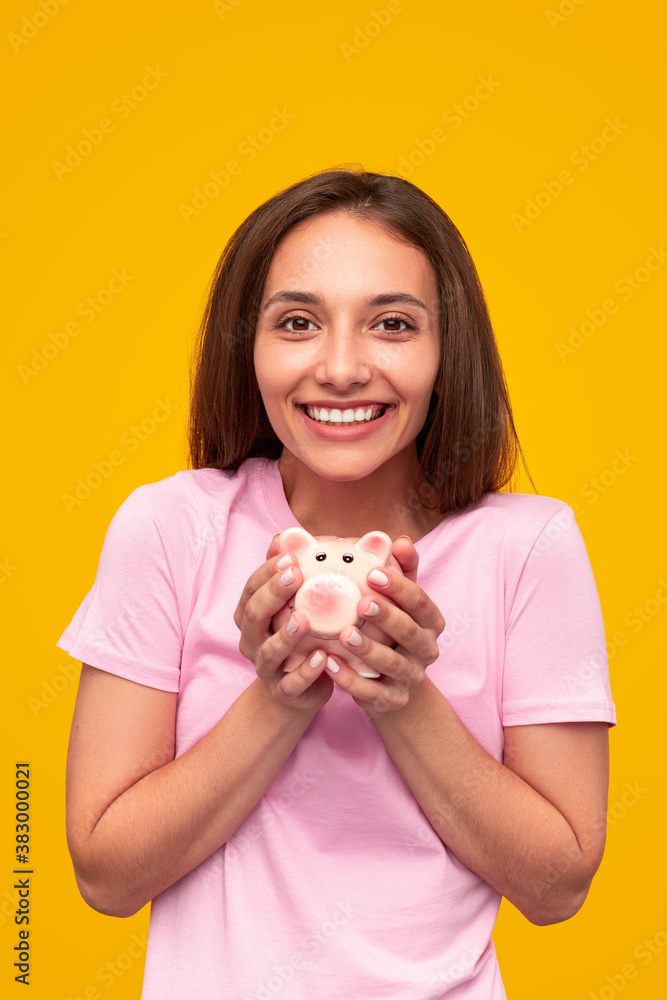 Delighted young woman with piggy bank