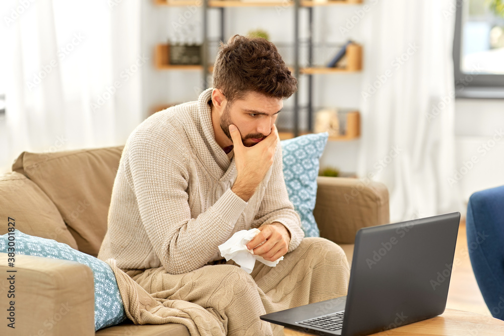 healthcare, technology and medicine concept - sick man in blanket having video call on laptop computer at home