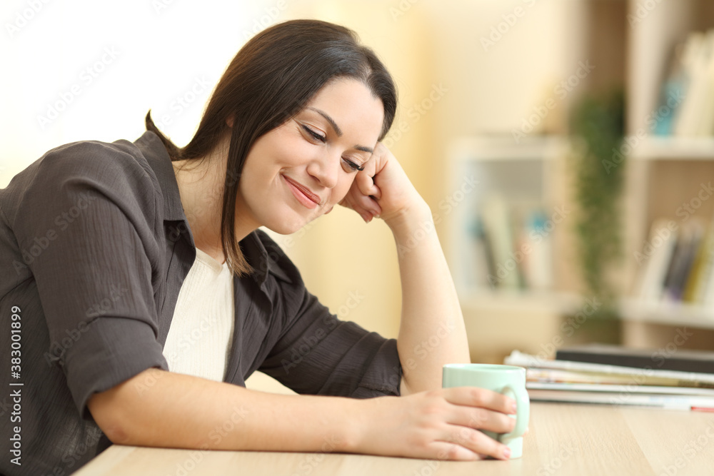 Happy woman thinking looking at coffee cup Happy woman thinking looking at coffee cup